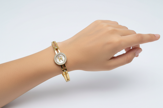 Gold bracelet with a Chanel logo on a light gray background