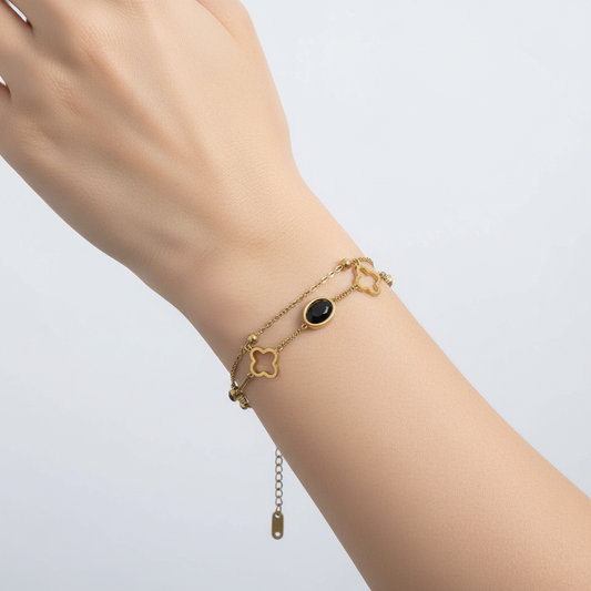 Gold bracelet with star and heart charms on a white background