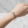 Silver bracelet on a textured surface with a light blue background