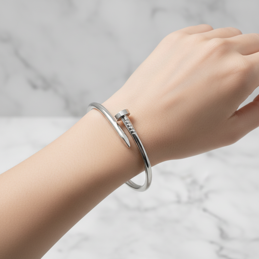 Silver bracelet on a textured surface with a light blue background