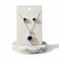 Jewelry set with heart-shaped blue gemstones on a white card with a marble base.