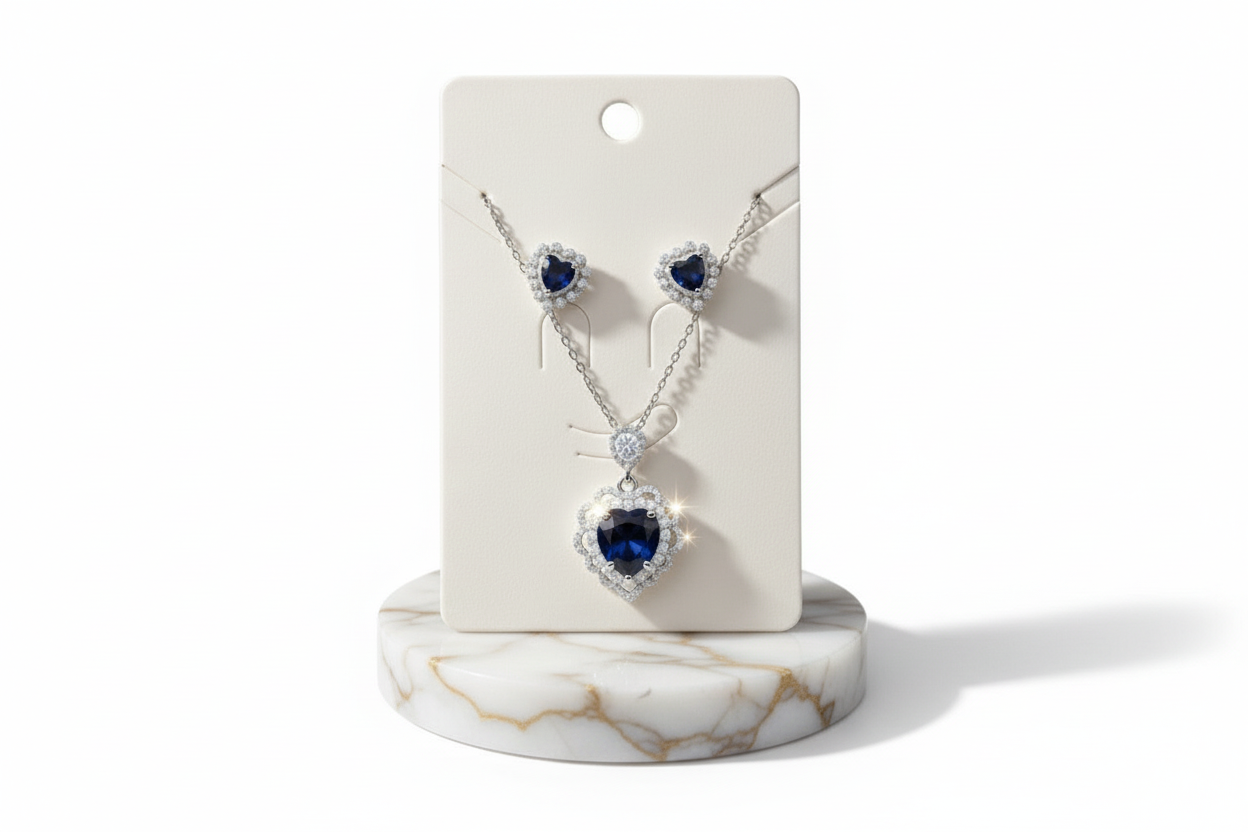 Jewelry set with heart-shaped blue gemstones on a white card with a marble base.