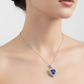 Woman wearing a silver necklace with a blue pendant on a plain background