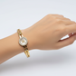Gold bracelet with a Chanel logo on a light gray background