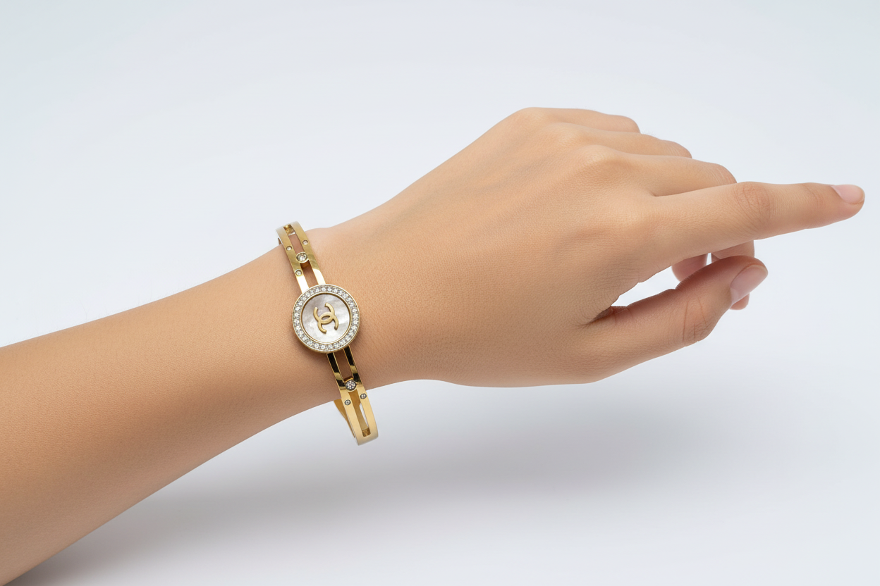 Gold bracelet with a Chanel logo on a light gray background