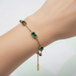 Gold bracelet with green gemstones on a light gradient background