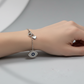 Silver bracelet with an eye-shaped pendant on a light gray surface