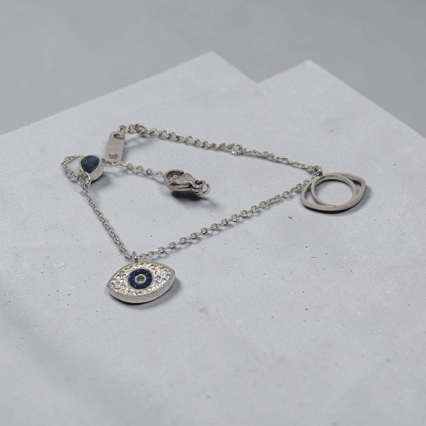 Silver bracelet with an eye-shaped pendant on a light gray surface