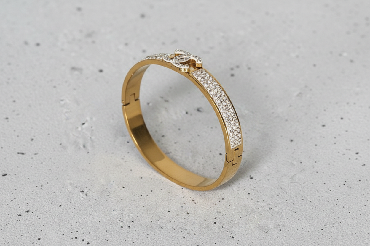 Gold bracelet with diamond accents on a concrete surface