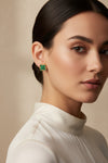 A pair of gold-tone four-leaf clover stud earrings with dark green malachite inlay, displayed on a light gray surface.
