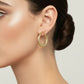 A pair of textured gold hoop earrings with fishhook backs, displayed on a light gray surface.