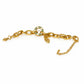 A gold chain bracelet with a circular interlocking link design and a small charm, displayed on a white curved tray against a textured light background.