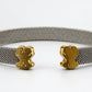 A silver-toned mesh cuff bracelet with two small gold-toned teddy bear charms, displayed on a white mannequin nose against a neutral light gray background.