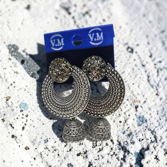 Pair of silver earrings on a blue V.M. branded card against a textured white background