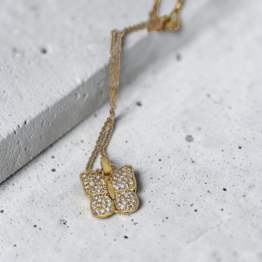 Gold butterfly necklace on a textured surface