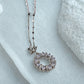 Silver necklace with a circular pendant on a light blue fabric background