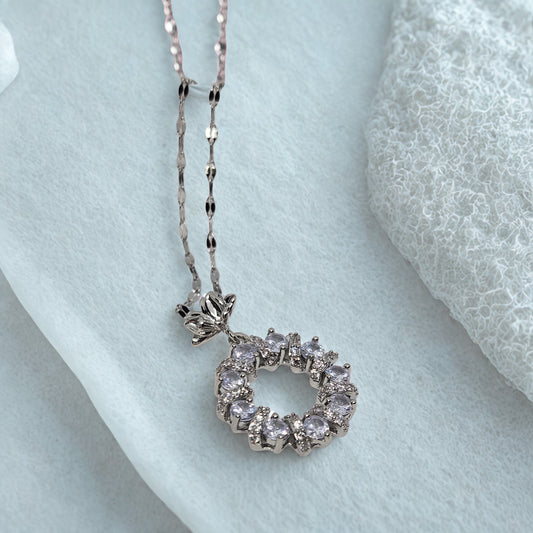 Silver necklace with a circular pendant on a light blue fabric background