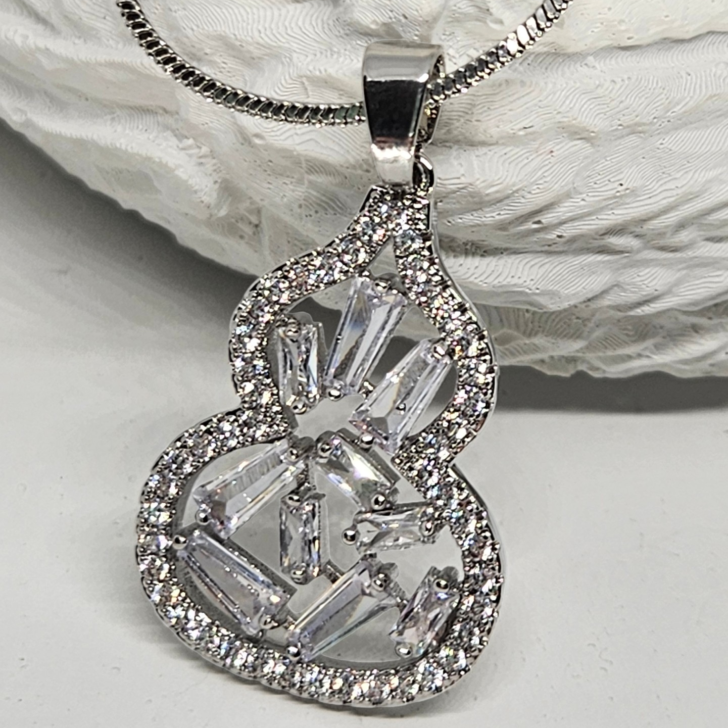 Silver necklace with a detailed pendant on a textured white surface