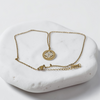 Gold necklace with a pendant on a white stone surface