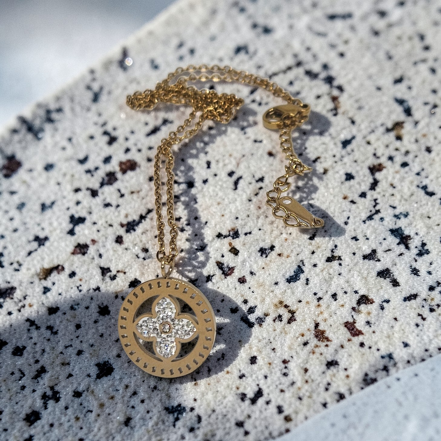 Gold necklace with a pendant on a textured surface