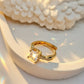 Gold ring with gemstone on a textured white surface, brand 'ZYLVA' visible.