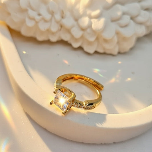 Gold ring with gemstone on a textured white surface, brand 'ZYLVA' visible.