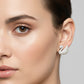 A pair of swan-shaped stud earrings covered in clear rhinestones on a silver-tone base, displayed on a light gray surface.