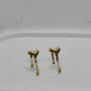 A pair of gold-toned, abstract-shaped stud earrings resting on a white display stand.