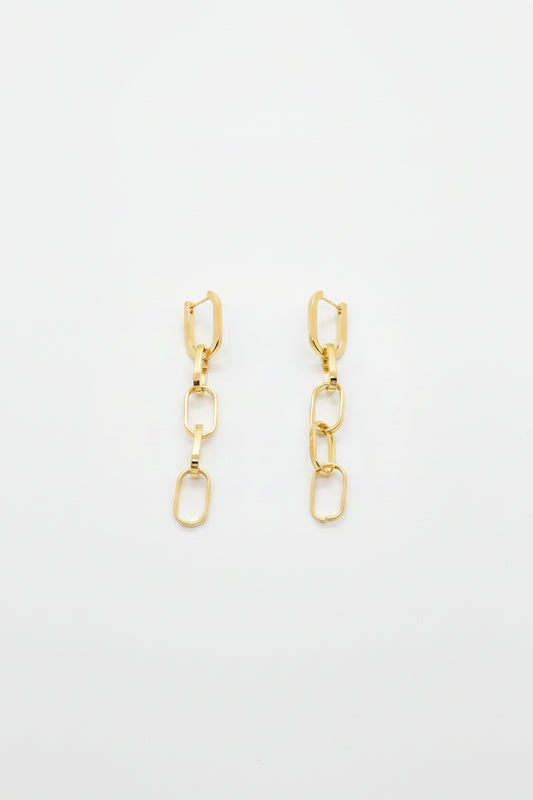 A pair of gold-toned drop earrings with geometric links and elongated oval charms, displayed on a white surface.