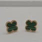 A pair of gold-tone stud earrings with green striped inlay, photographed on a plain light gray surface.