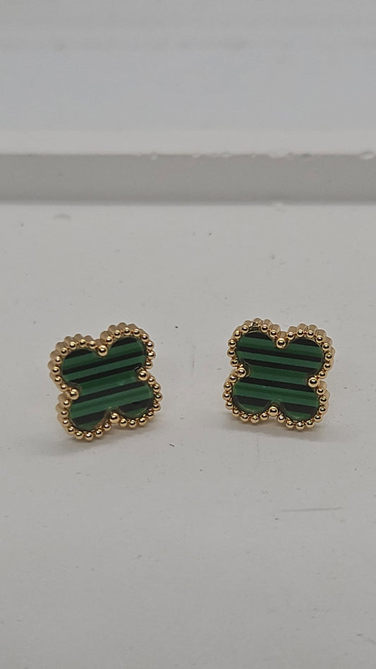 A pair of gold-tone stud earrings with green striped inlay, photographed on a plain light gray surface.