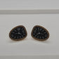 A pair of gold-tone triangular studs designed to look like clock faces with black centers and white hands.