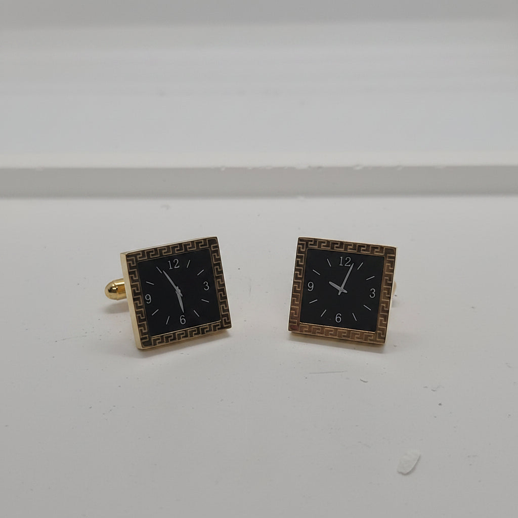 A pair of square earrings designed to look like clock faces, featuring black centers with white numerals and hands, surrounded by gold-tone borders.