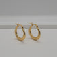 A pair of textured gold hoop earrings with fishhook backings, displayed on a light gray surface.